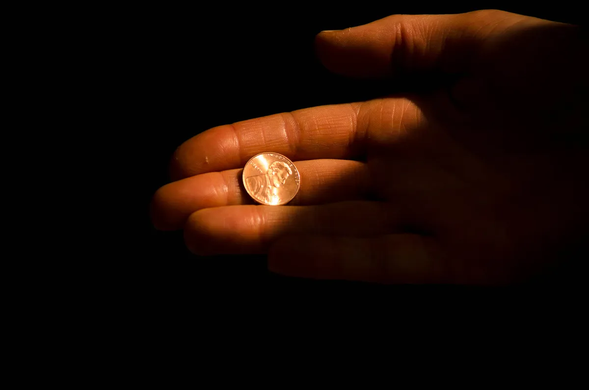 A hand holding a penny.