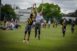 A player catching a frisbee over another player.