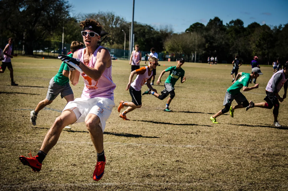 A player catching a frisbee with other players running in the background.