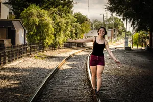 A girl walking on the train tracks.